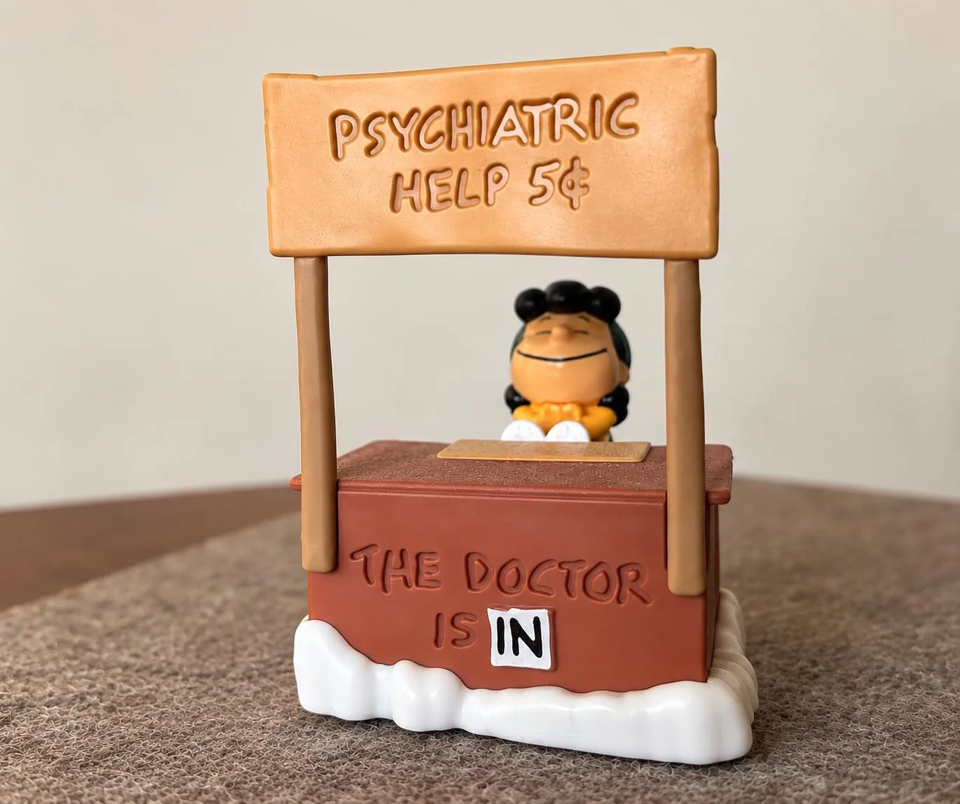 Kleine Figur an einem Beratungsstand mit den Schildern „Psychiatric Help 5¢“ und „The Doctor is in“